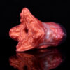A silicon sex toy for men resting on a black surface. The toy features red color and suction cups on its tentacles.