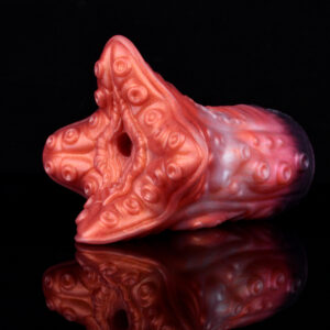 A silicon sex toy for men resting on a black surface. The toy features red color and suction cups on its tentacles.