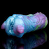 A male masturbator resting on a reflecting black surface. The sex toy features a unique form und vibrant colors.
