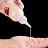 A close-up of a persons hand pouring lubricant, highlighting the liquid form.