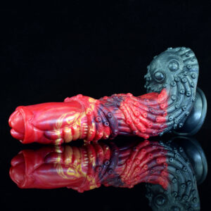 A red and black fantasy dildo pops against a black backdrop, highlighting its colors and shape in a dramatic way.