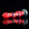 A red and black fantasy dildo with a shiny reflection, highlighting its unique design and texture.
