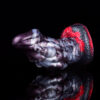 A close-up of a thick and girthy dragon dildo in front of a black background.