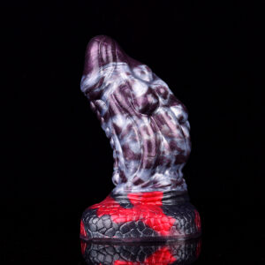 A thick dragon dildo standing on its solid base in front of a black background.