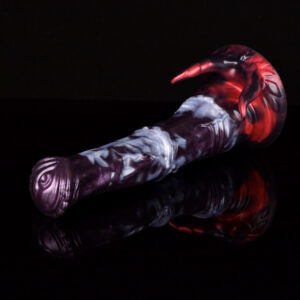 A close up of a fantasy horse dildo laying on a black and reflecting surface with a black background.