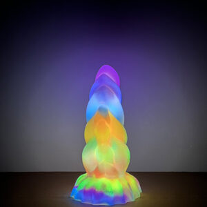 A stunning dildo radiates rainbow hues, beautifully lit and displayed on a table, creating a captivating atmosphere.