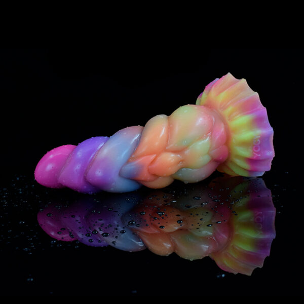 A vibrant and colorful fantasy dildo, laying on a black shimmering surface with water drops on it.