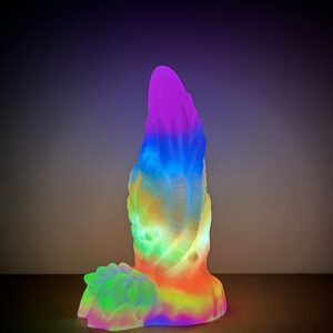 A glowing monster dildo standing in the dark brightening up a wall in the background with its vibrant glow.