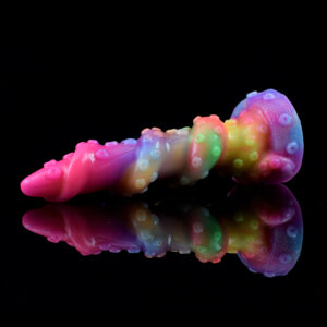 A colorful tentacle dildo laying on a reflecting black surface. The dildo has a spiral form and little suction cups on its shaft.