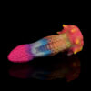 A colorful dragon dildo in the form of a tentacle laying on a black and reflective surface. The dildo has small suction cups all over its shaft.