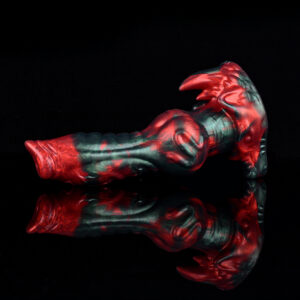 A werewolf dildo resting on a black and reflecting surface. The black and red dildo features a big knot and a horn on its solid base.